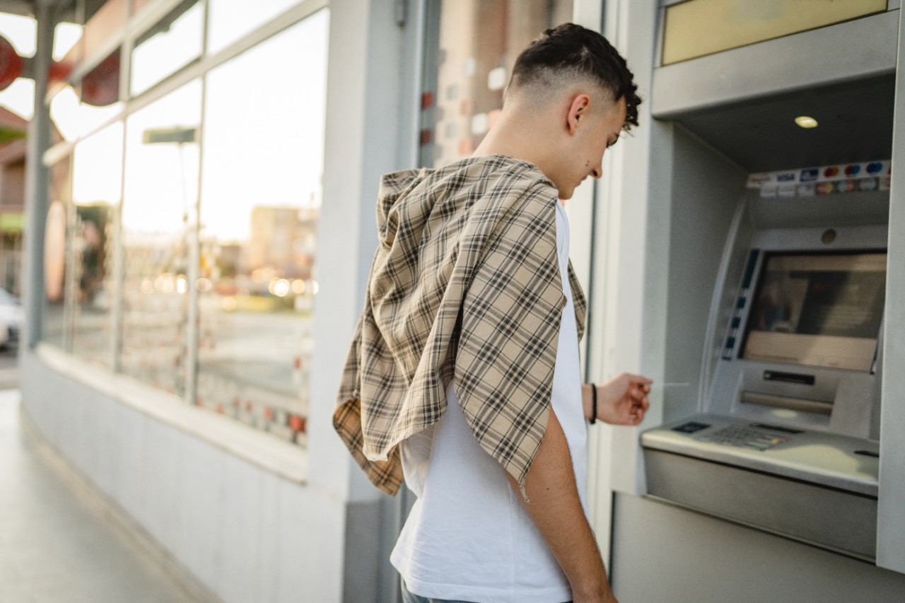 Marqeta partnership man teenage student using credit card and withdrawing cash at the ATM